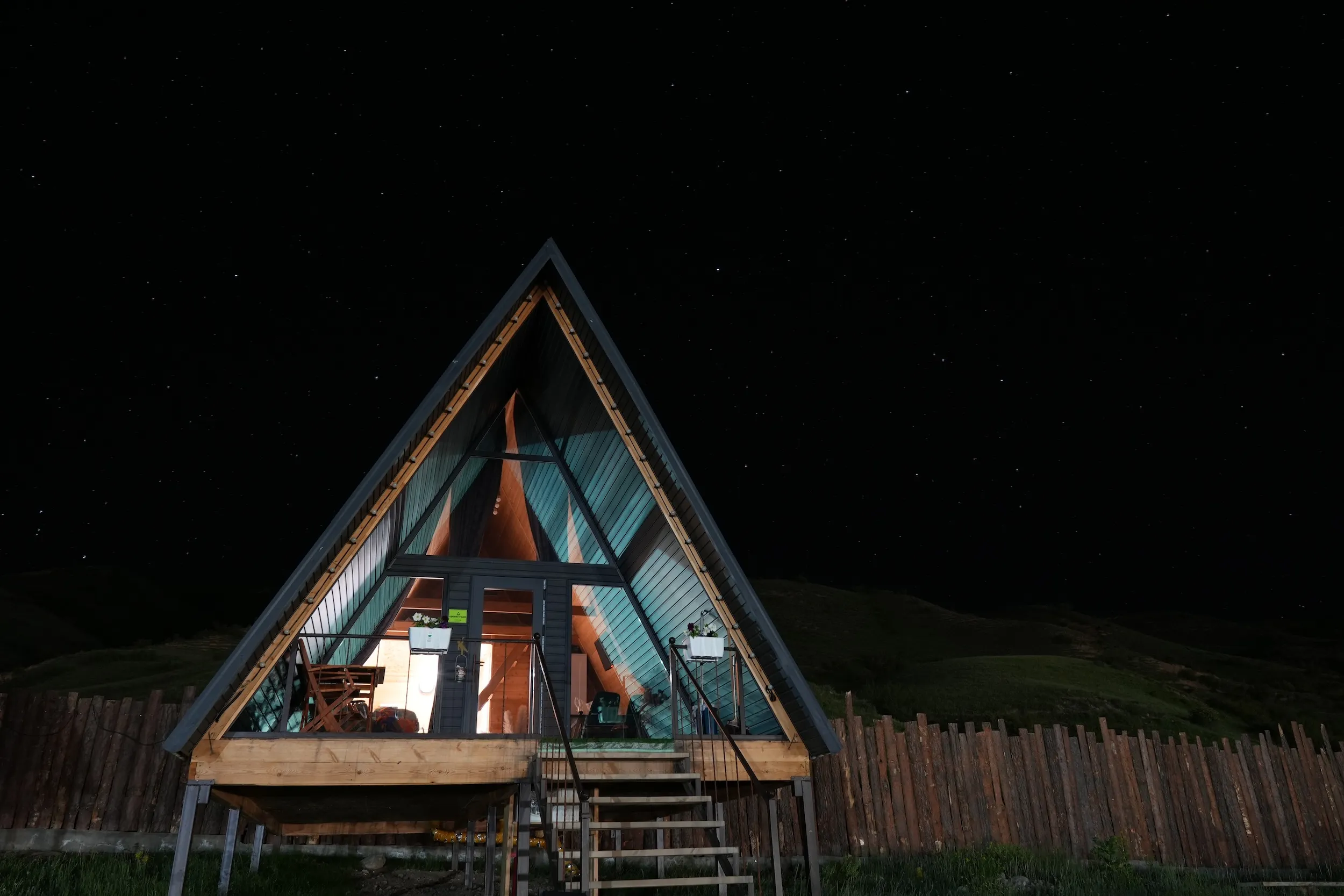 The view is of the A-Frame accommodation that Tanya and her friends stayed in while in Saty, Kazakhstan. It is dark outside and there are a lot of stars visible in the sky behind the A-Frame.